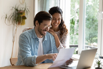 Happy wife and husband read good news in received document letter correspondence feel satisfied...