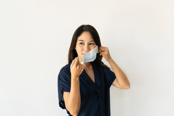 Beautiful young Asian woman wearing surgical face mask before leave the house. New normal, health care concept. Copy space
