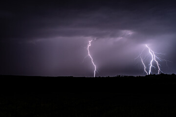 Naklejka na ściany i meble Multiple lightning strikes lighting up the sky on a summer evening during a thunderstorm