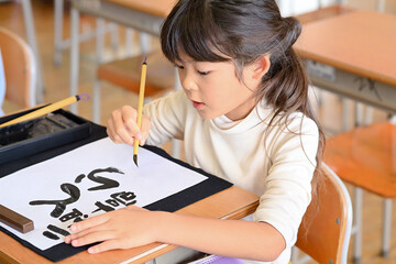教室で習字の勉強　小学生の女の子　寅年の筆書き