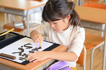 教室で習字の勉強　小学生の女の子　寅年の筆書き