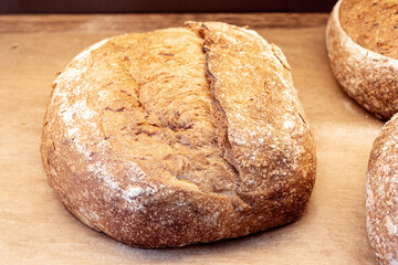 Close-up of loaf of brown homemade bread, brown dark bread with grains on the shop shelf