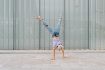Young caucasian athletic gymnast woman outdoors soing cartwheel sportive and dynamic