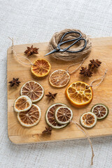 Weihnachtsschmuck getrocknete Orangenscheiben und Anis, Flatlay mit Schere Bindfaden und Holzablett