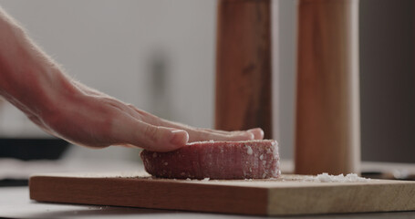 rubbing seasoning into beef steak on wood board