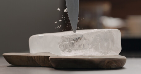 man breaking ice block on olive wood board