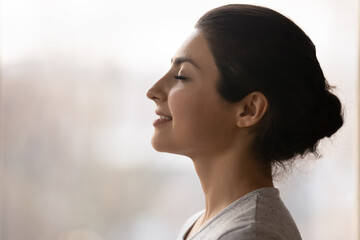 Meditation. Side profile shot of happy serene young indian female face. Calm millennial ethnic lady...