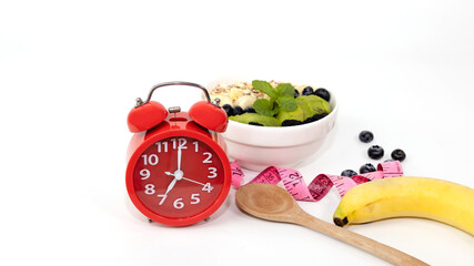 Selective focus with Red alarm clock on white background which Intermittent fast program plan of diet -Healthy eating with yogurt parfait it time in the morning