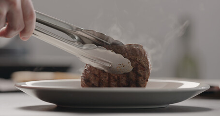 man put hot steak on white plate