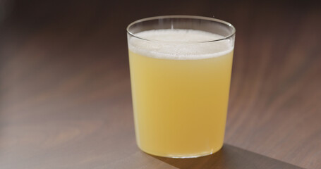 orange juice from glass bottle into tumbler glass on walnut table