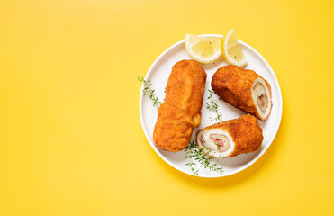 French traditional cuisine crispy, creamy chicken cordon bleu on yellow background. top view.