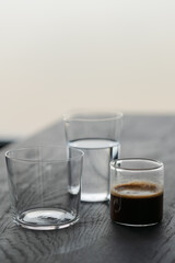 Ingredients for espresso tonic with clear ice cube in tumbler glass on oak wood table with copy space