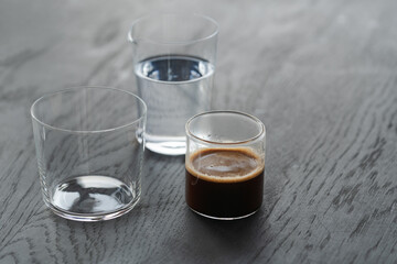 Ingredients for espresso tonic with clear ice cube in tumbler glass on oak wood table with copy space