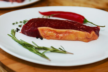 Meat cooked for barbecue. The dish is in a white plate. Steak, rosemary