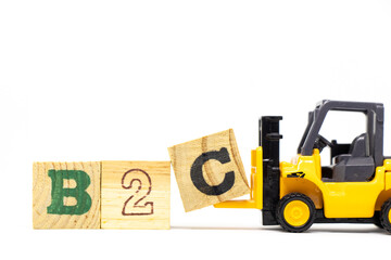Toy forklift hold letter block c to complete word b2c (abbreviation of business to consumer) on wood background