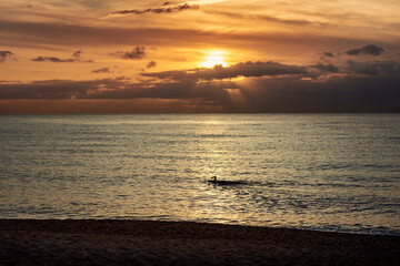 Fototapeta na wymiar person swimming alone in the sea at sunset
