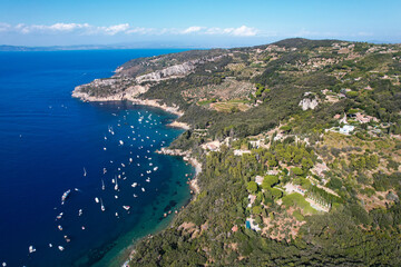 Fototapeta na wymiar View from above, stunning aerial view of a bay with boats and luxury yachts sailing on a turquoise, clear water surrounded by cliffs. Porto Santo Stefano, Monte Argentario, Italy.