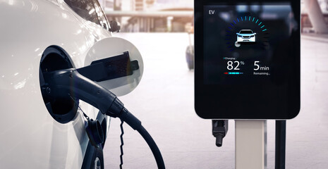 Electric car charging station charging power battery using pump cable, visual display city sunset...