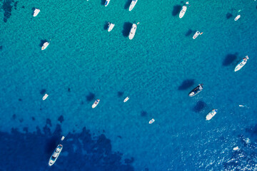 View from above, stunning aerial view of a bay with boats and luxury yachts sailing on a turquoise, clear water. Porto Santo Stefano, Italy.