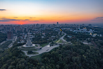 Monument Motherland in Kiev from a bird's eye view against the background of the evening sky. evening Kiev and the main monument of the city. the setting sun and burning city lights.