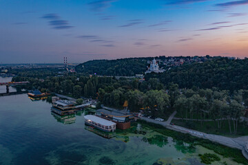 Evening Kiev from a bird's eye view. Architectural monuments. The light of lanterns and evening lights. City on the Dnieper. White buildings. Sunset.
