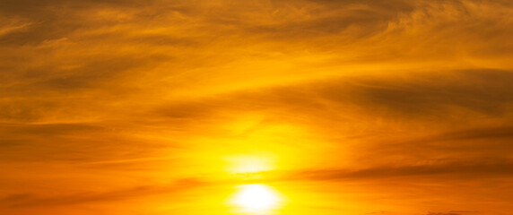 The rising sun shines brightly in the orange sky.