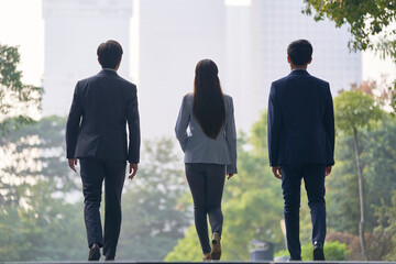 rear view of team of young asian business people walking outdoors on street