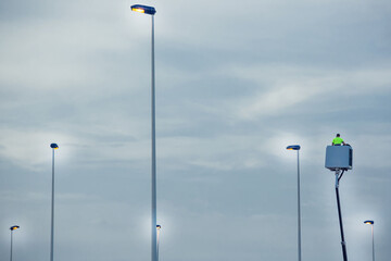Light pole repairing. Worker in lift bucket installing new lights
