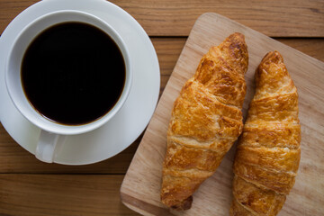 croissant and cup of coffee on a wooden table. 