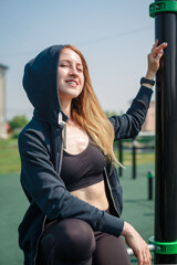 Girl in a tracksuit with a hood on her head on the playground. Workout. Healthy lifestyle.