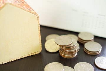 Thai coin 5 baht with model house and blur calendar on black wooden backgound. plant saving growth cash money and investment income for future. business or finance concept.