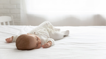 Sleepy silent few month infant resting in double bed with white sheet. Cute adorable peaceful baby...
