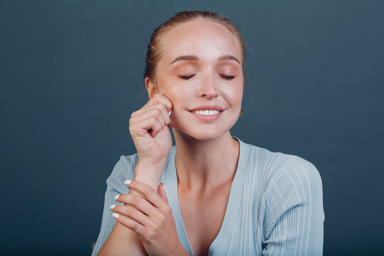 Millenial young woman blonde hair portrait doing face yoga self facebuilding massage for face skin stretching flex building and lifting