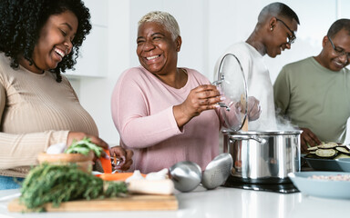 Happy African family having fun in modern kitchen preparing food recipe with fresh vegetables - Food and parents unity concept