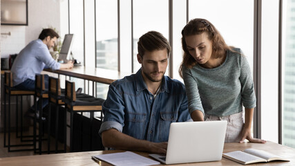 Pensive millennial Caucasian colleagues work online on modern computer engaged in team discussion...