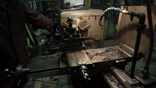 a robot on an old lathe grooving a metal part in a dark workshop	