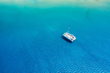 An aerial view of the yacht on the azure sea. Transparent clear water in the Mediterranean Sea. Summer vacations and travels on a sailing yacht. Summer relaxation.