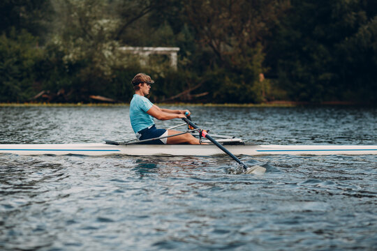 Sportsman single scull man rower rowing technique on boat. Paddle oar splash movement motion