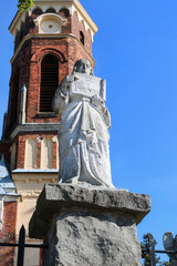 KLECZA DOLNA, POLAND - SEPTEMBER 11, 2021: A stone figure of an angel in front of the entrance to the Church of st. Lawrence Martyr in Klecza Dolna, Poland. - obrazy, fototapety, plakaty