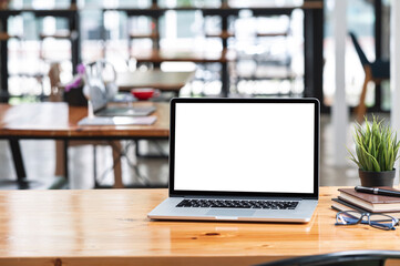 Blank screen laptop computer and supplies on wooden table in contemporary office room with copy space.