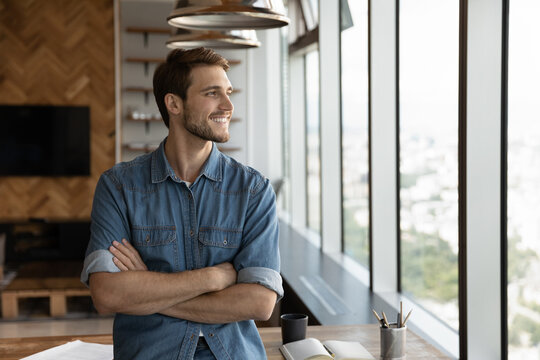 Smiling Male Employee Stand At Workplace Look In Window Distance Thinking Pondering Of Future Caress Opportunities Perspectives. Happy Man Imagine Visualize Success. Business Vision Concept.