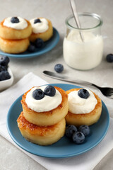 Delicious cottage cheese pancakes with blueberries, honey and sour cream on light table