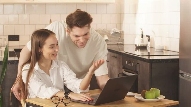 Man and woman look at screen of laptop, spend free time at home. They want to do purchase online