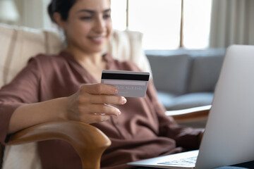 Ecommerce client. Young mixed race woman web shop customer using bank card to make safe secure...