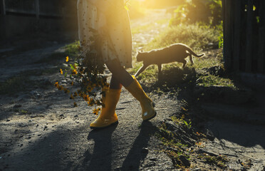 Little girl in yellow ruber shoes. Child walking in the wood at sunset