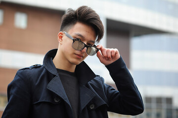 Asian young man in a coat on the street