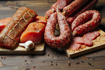 Various types of meat and sausages on wooden table, served on board, closeup