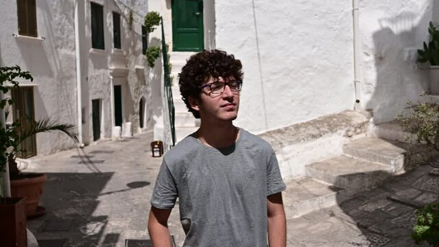 Amazing footage in the white alleys of Ostuni, Puglia, Italy. A nice Caucasian boy walks along them and curiously observes this fascinating and picturesque environment.