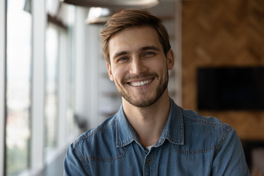 Profile picture of smiling successful young Caucasian businessman or boos look at camera pose in office. Headshot portrait of happy millennial male employee at workplace. Employment, hr concept.