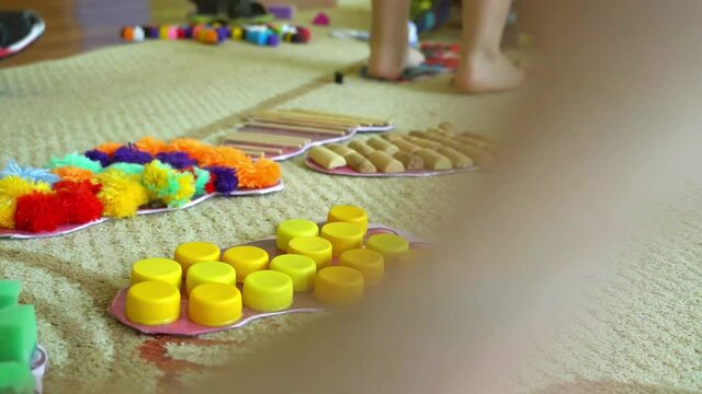 Children's legs go on a multi-colored massage orthopedic rug against a colored floor.